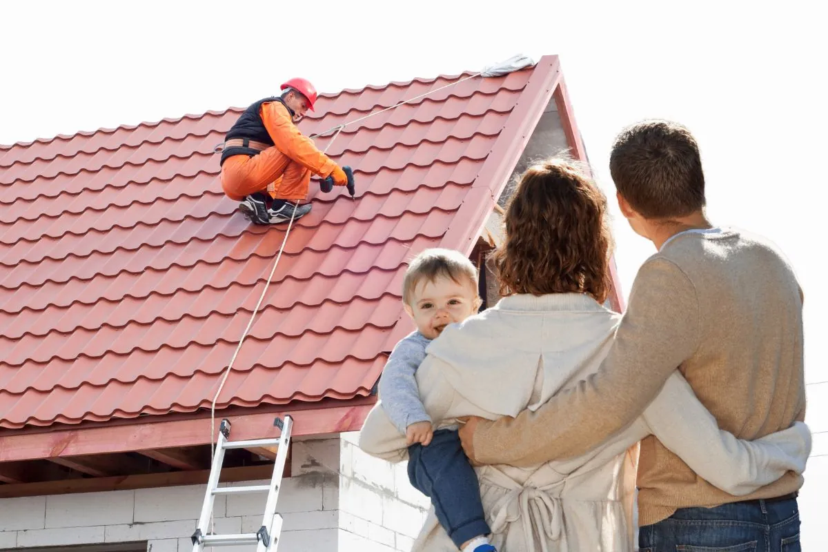 young family looking at house roof with contractor